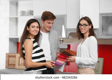 Beautiful Young Couple Talking With Designer In Kitchen