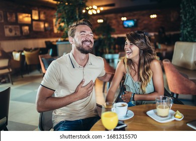 Beautiful young couple using a smartphone and smiling while sitting in the cafe