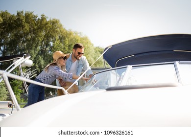 A beautiful young couple watches a motor boat that they intend to buy.