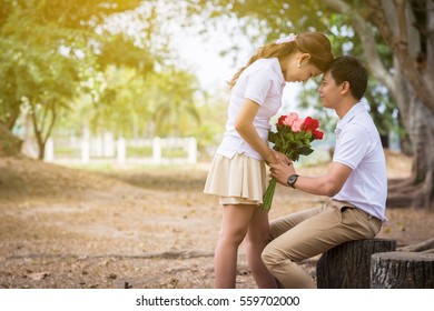 Beautiful Young Couple With White Coats Standing On The Bridge. Man Send A Bouquet Of Flowers To A Woman.  Vintage Tone.