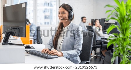 Beautiful young customer service representative wearing headset working on computer at cal center office.