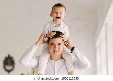 Beautiful Young Dad And Son Cuddle And Play In Smart Clothes At Home