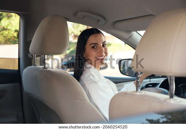 Beautiful young driver\
sitting in modern car