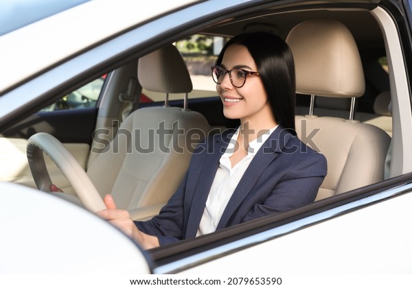Beautiful young driver\
sitting in modern car
