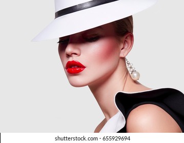 Beautiful young elegant girl in a white gown and a black dress with valans. Portrait on white background. Bright makeup - red lips, arrows in front of eyes. Fashionable attire, gamur, luxury, luxury. 