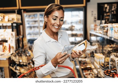 Beautiful young and elegant woman buying some healthy food and drink in modern supermarket or grocery store. Lifestyle and consumerism concept. - Shutterstock ID 2277123205