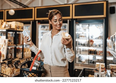 Beautiful young and elegant woman buying some healthy food and drink in modern supermarket or grocery store. Lifestyle and consumerism concept. - Powered by Shutterstock