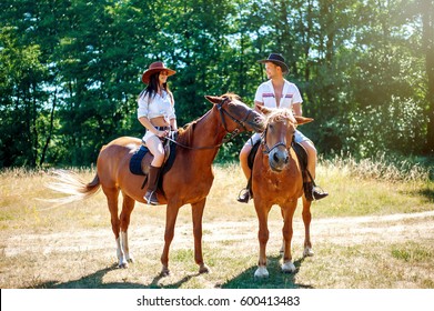 Beautiful Young Enamored Couple. Horseback Riding In Nature. A Bright Sunny Day. Summer Joy. Cowboy Hats.