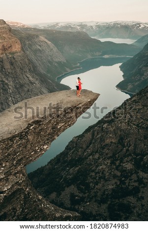 Similar – Man sitting on a cliff of a fjord with low sun on the European Arctic Ocean