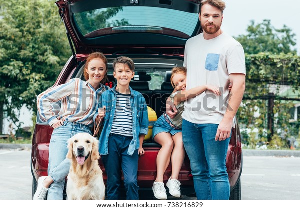 beautiful young family with dog standing next to car\
ready for trip