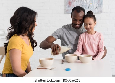 Beautiful Young Family Pouring Milk Into Cereal Breakfast