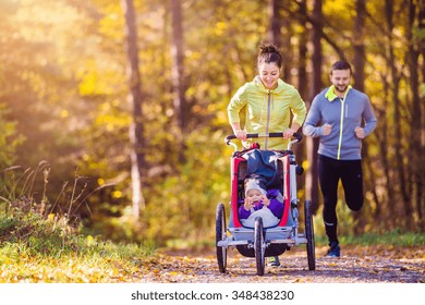 Beautiful Young Family Running Outside In Autumn Nature