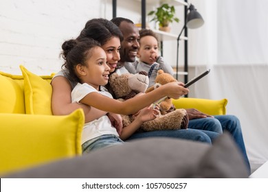 beautiful young family watching tv together on couch