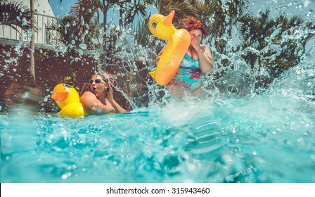 Beautiful young fat woman is jumping splash into the summer water pool with yellow duck lifebuoy