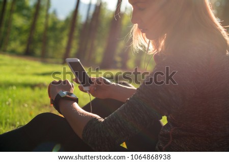 Beautiful young female athlete using fitness app on her smart watch to monitor workout performance. Lifestyle wearable technology concept with lensflare.