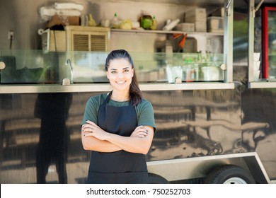 Beautiful young female cook and entrepreneur standing outdoors with her food truck in the background - Powered by Shutterstock