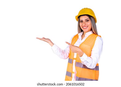 Beautiful Young Female Engineer Or Supervisor, Wearing Safety Gear, Pointing To The Side On White Background With Room For Text Or Copy Space. Concept Of Empowered Woman, Professional Woman