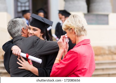 beautiful young female graduate hugging her father at graduation