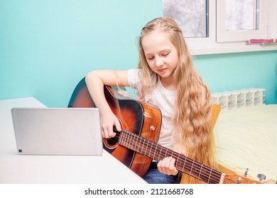 A Beautiful Young Female Guitarist Will Learn To Play The Guitar Online. The Girl Looks At The Guitar.