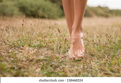 Beautiful young female legs walking on the grass in summer