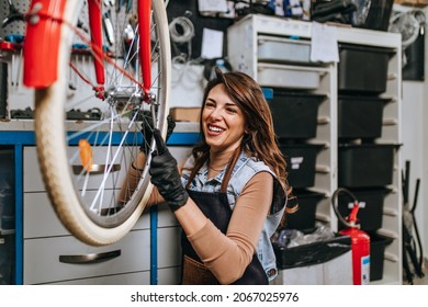 Beautiful young female mechanic enjoying while repairing bicycles in a workshop.	 - Powered by Shutterstock