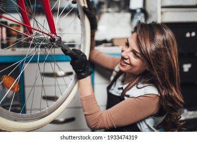 Beautiful young female mechanic having fun and enjoying while repairing bicycles in a workshop.	 - Shutterstock ID 1933474319