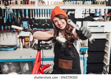 Beautiful young female mechanic having fun and enjoying while repairing bicycles in a workshop.	 - Powered by Shutterstock