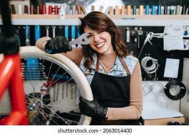 Beautiful young female mechanic having fun and enjoying while repairing bicycles in a workshop.	 - Powered by Shutterstock