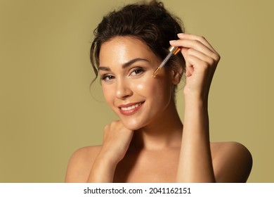 Beautiful young female moisturizing glowing facial skin by serum collagen and hyaluronic acid. Hands with serum dropper near girl face. Skincare and rejuvenation cosmetics for natural woman beauty. - Powered by Shutterstock