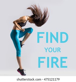 Beautiful young fit modern dancer lady in blue sportswear warming up, working out, dancing with her long hair flying, full length, studio image on gray background. Motivational phrase "Find your fire"