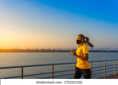 Beautiful young fitness Asian woman running and exercise with wearing a protective mask COVID-19 an outdoor workout on the riverwalk in the morning for lifestyle health.