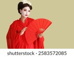 Beautiful young geisha with fan on green background