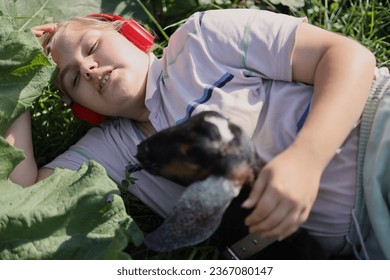 Beautiful young girl with a baby goat in a green summer garden. Cute Nubian goat