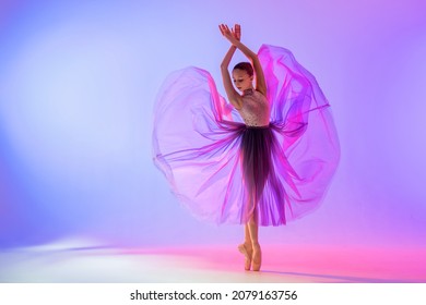 Beautiful young girl ballerina in pointe shoes and a pink leotard silhouette on a bright blue background.