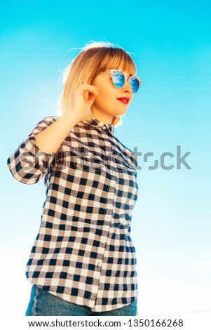 Similar – Porträt einer blonden Frau mit Hut, Sonnenbrille und roten Lippen, die bei Sonnenuntergang die Natur genießt.