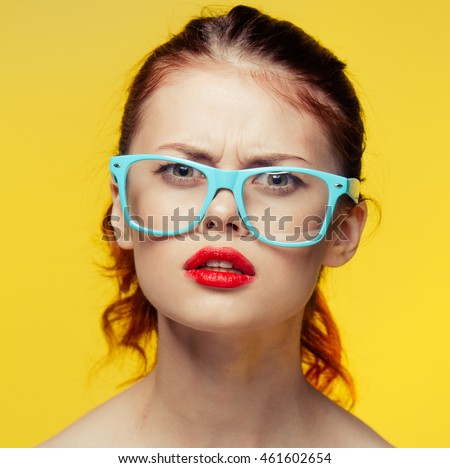 
beautiful young girl in blue glasses on yellow background