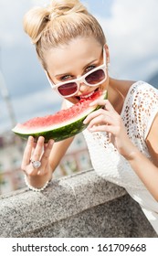 Beautiful Young Girl With Bow Tie Hair In White Summer Dress Wearing Sunglasses Bites Juicy Watermelon