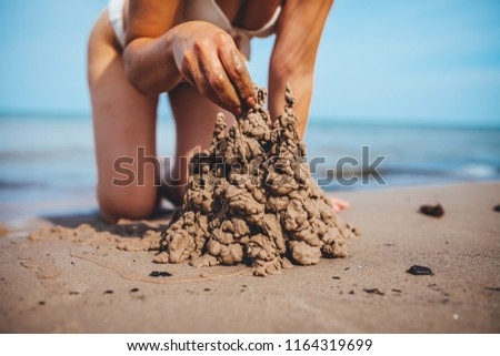 Beautiful young girl builds a sand castle on the beach, summer time on the beach 
