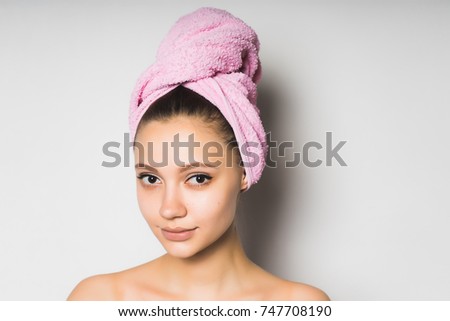 beautiful young girl with clean skin, with a pink towel on her head smiling and looking at the camera
