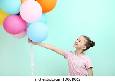 Beautiful young girl with colored balloons on mint background