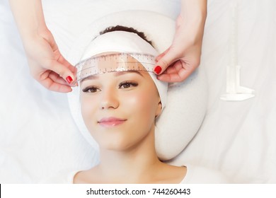 Beautiful young girl correction of eyebrows in a salon.professional care for face.Permanent Makeup for brows. woman tweezing her eyebrows in salon.Cosmetology Treatment.Make-Up.Microblading eyebrows.