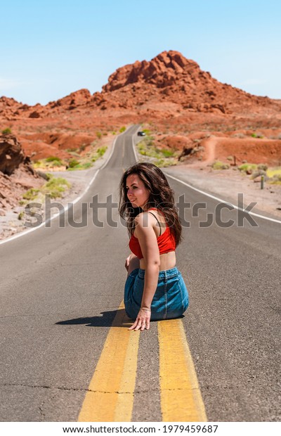 Beautiful young girl in a denim skirt on a scenic\
road in Valley of fire,\
Nevada