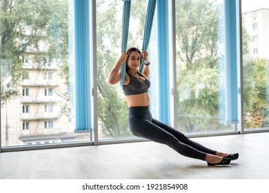 beautiful young girl doing aerobic exercises in fly yoga on canvases near windows in gym - Powered by Shutterstock