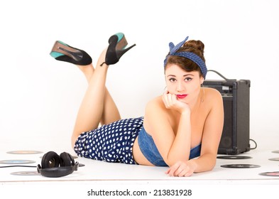 Beautiful Young Girl With Hand Under Her Chin In Retro Clothes And Hairstyle Representing Pinup Style Lying On The Floor With Vynil Records Isolated On White