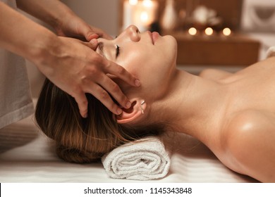 Beautiful young girl having face massage in spa salon