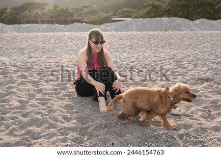 beautiful young girl and her cocker spaniel dog having fun on the beach on a hot spring day