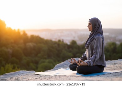 Beautiful young girl in a hijab meditates and practices yoga on a background of sunset and landscape. The concept of a healthy lifestyle - Powered by Shutterstock