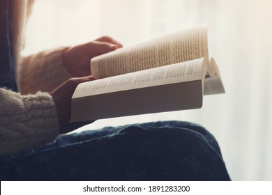 beautiful young girl holding open book and reading novel at home - Powered by Shutterstock