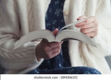 beautiful young girl holding open book and reading novel at home, cozy 