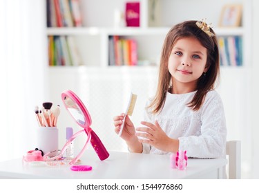 beautiful young girl, kid brushing the hair, applying makeup with toy beauty set